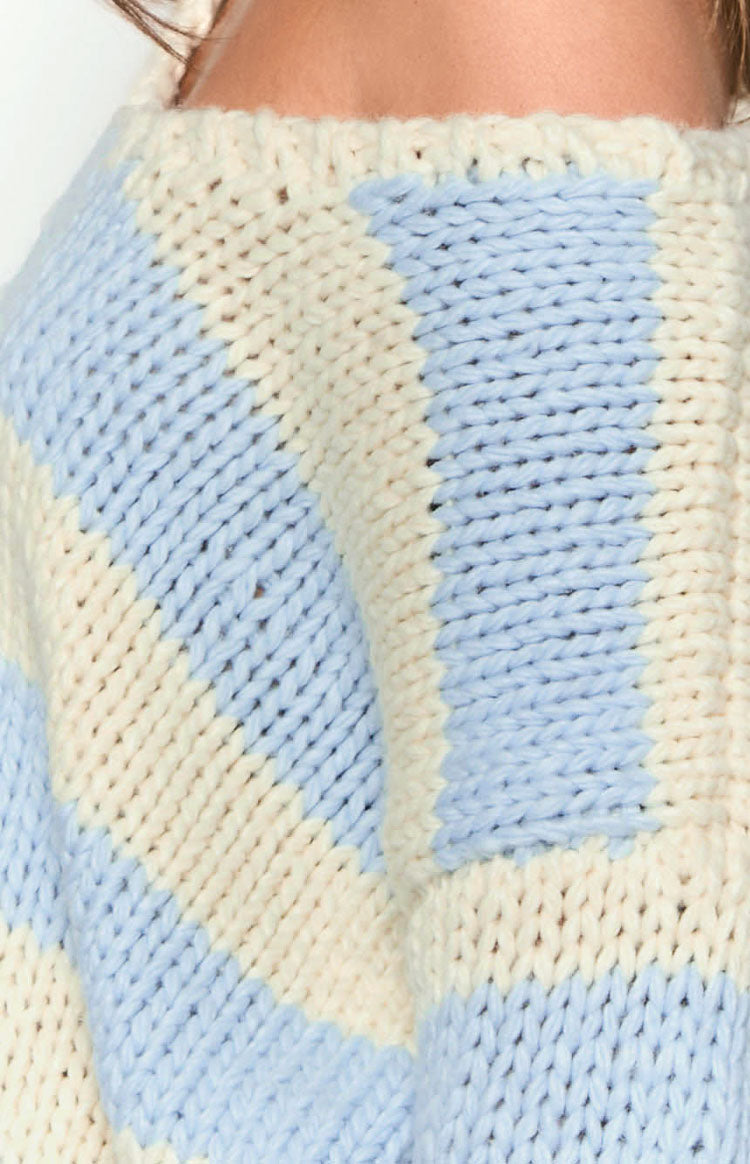Close-up of the thick, chunky knit texture and light blue and cream stripes of the sweater