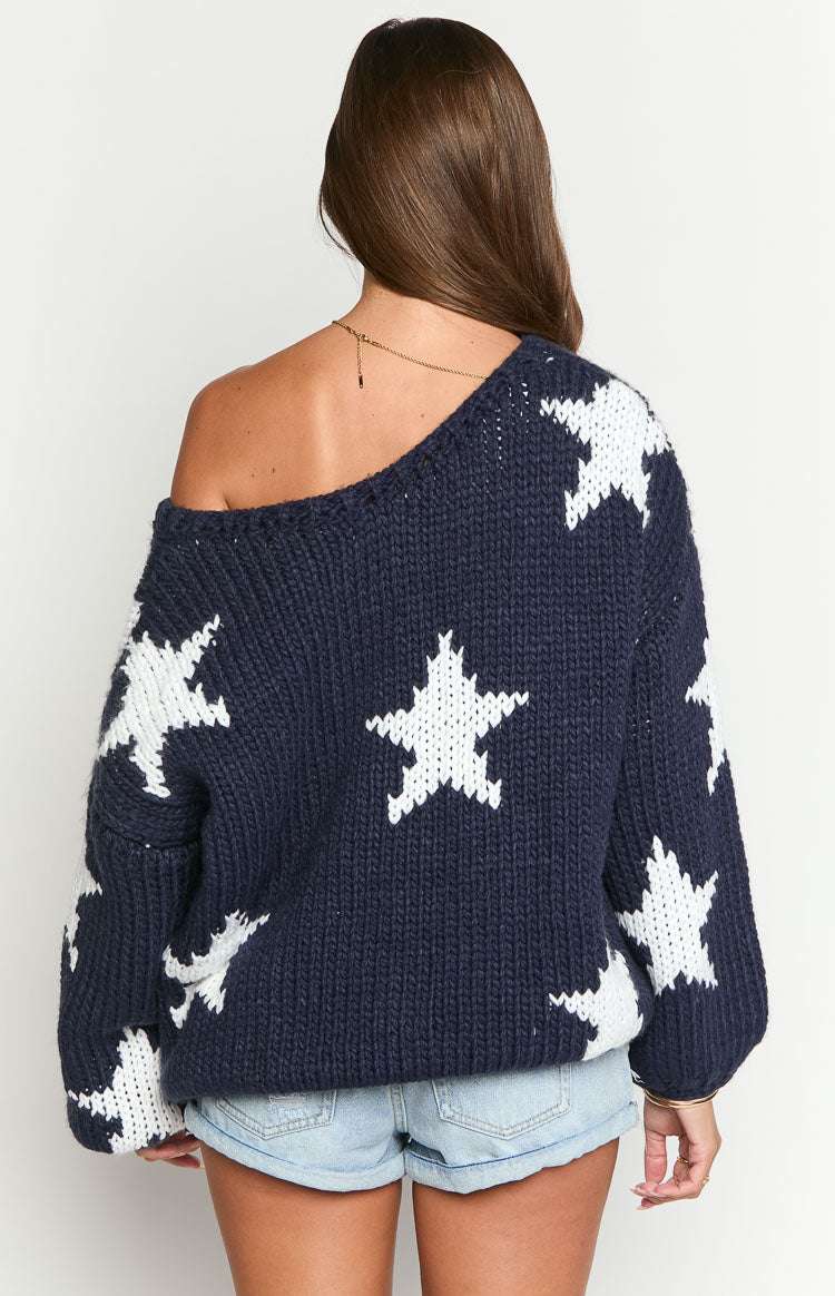 Rear view of a navy chunky knit sweater with white star pattern, featuring an off-shoulder design