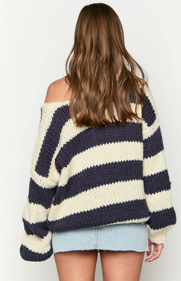 Rear view of a navy and cream striped chunky knit sweater with an off-shoulder neckline