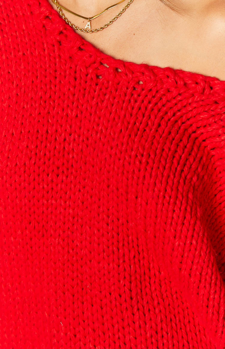 Close-up of the red chunky knit sweater showing the visible stitches and wide, ribbed neckline edge