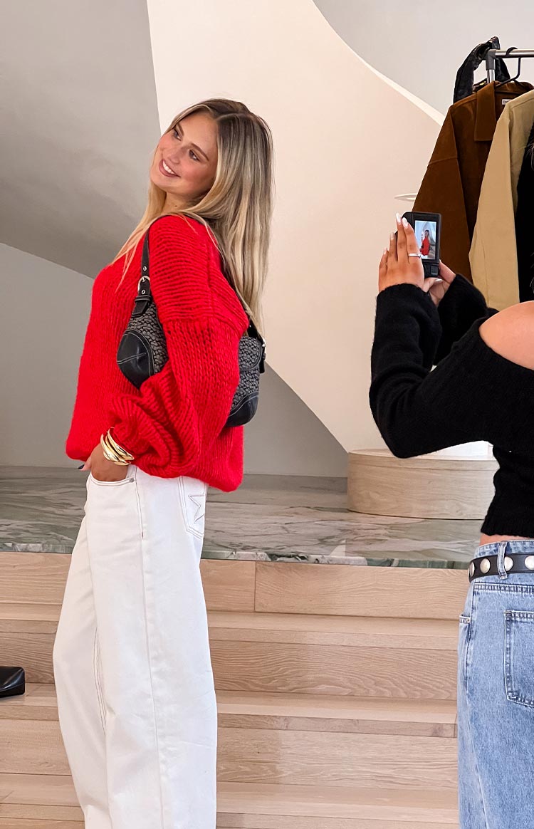 Side view of a red chunky knit sweater with a relaxed fit and long sleeves