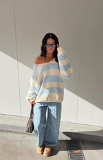 Light blue and cream striped chunky knit sweater with a wide V-neck worn off one shoulder