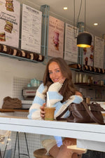 Light blue and cream striped chunky knit sweater with a wide off-shoulder neckline and relaxed long sleeves