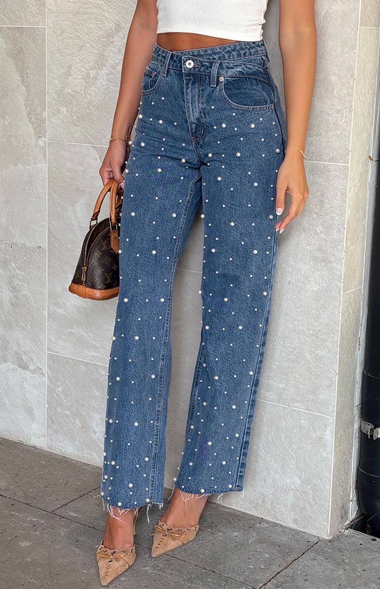 Full length view of mid wash blue high waisted jeans with all-over pearl embellishments and a raw hem