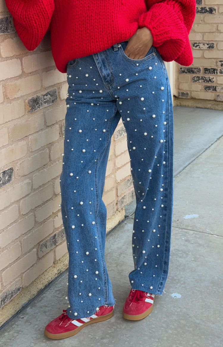 Mid wash denim high waisted jeans with scattered pearl embellishments and a distressed raw hem