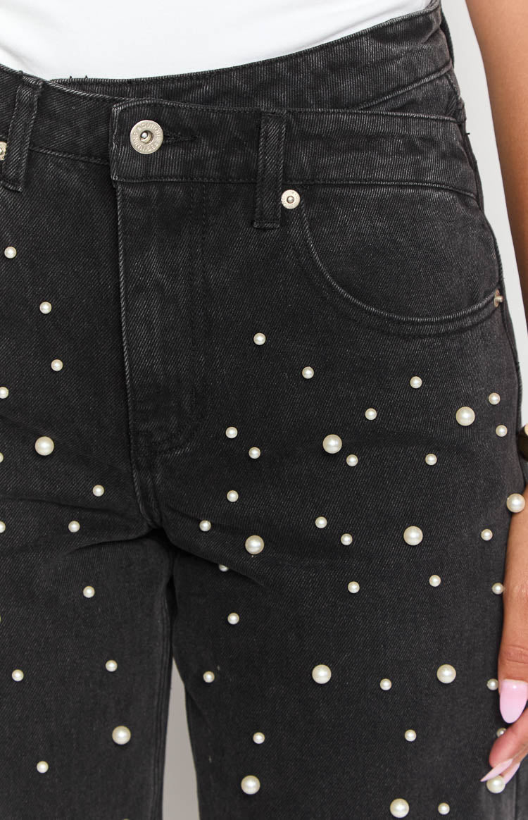 Close-up of the black high waisted jeans showing the button closure and scattered white pearl embellishments