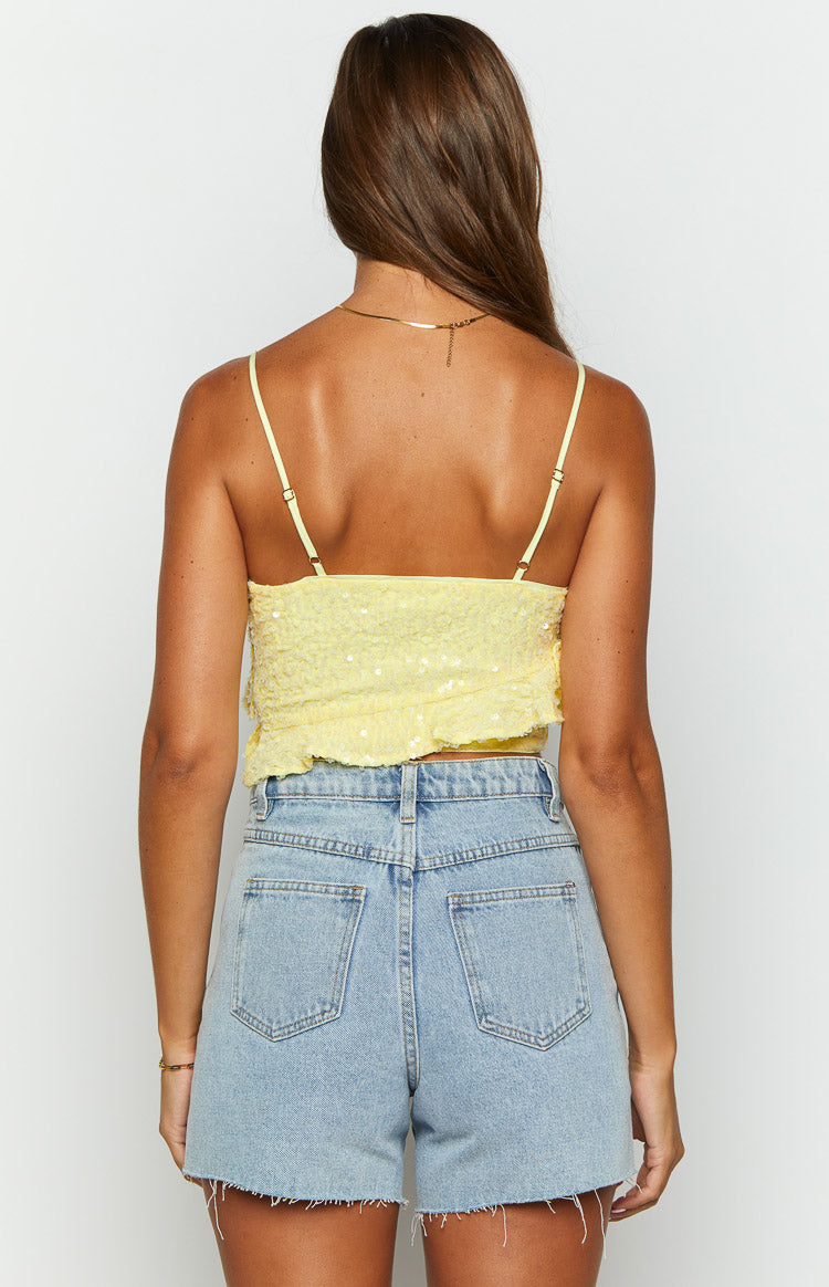 Rear view of a yellow sequin crop top with adjustable spaghetti straps and a ruffled hem