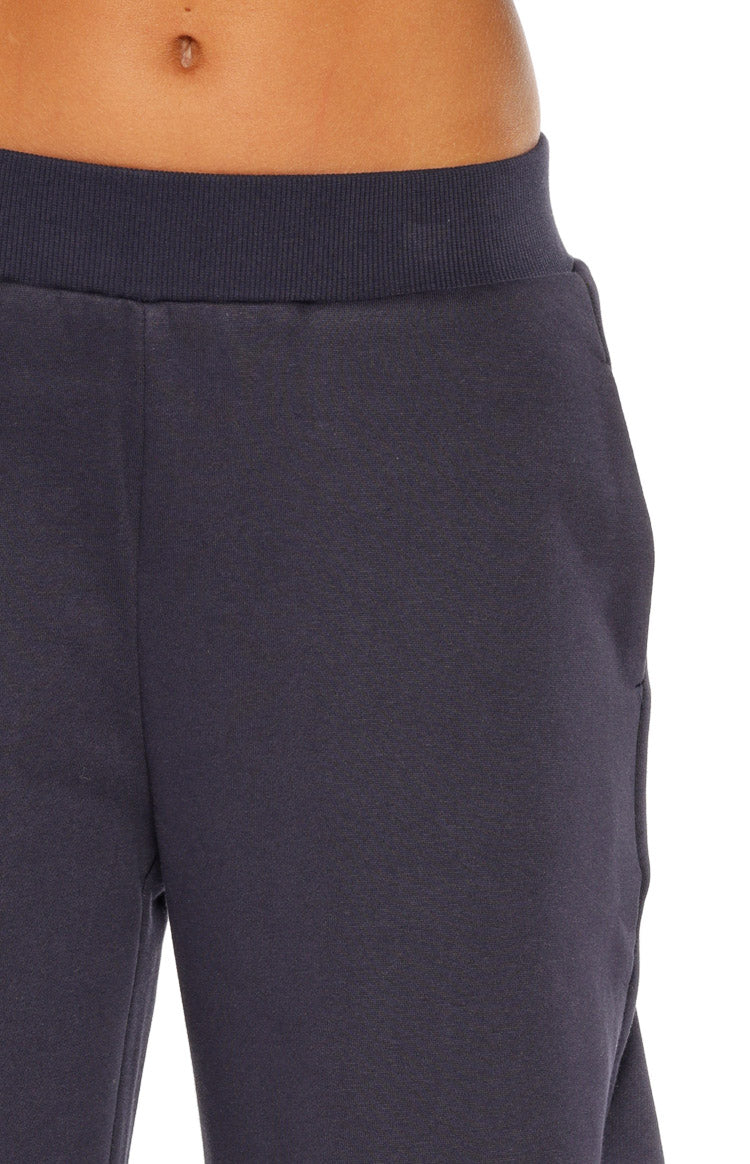Close-up of the navy track pants showing the ribbed elastic waistband and side pocket