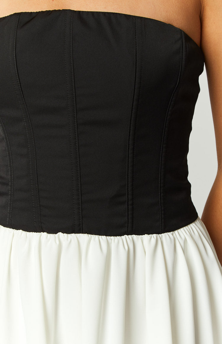 Close-up of the black structured corset bodice with vertical boning seams and the gathered white skirt of the mini dress