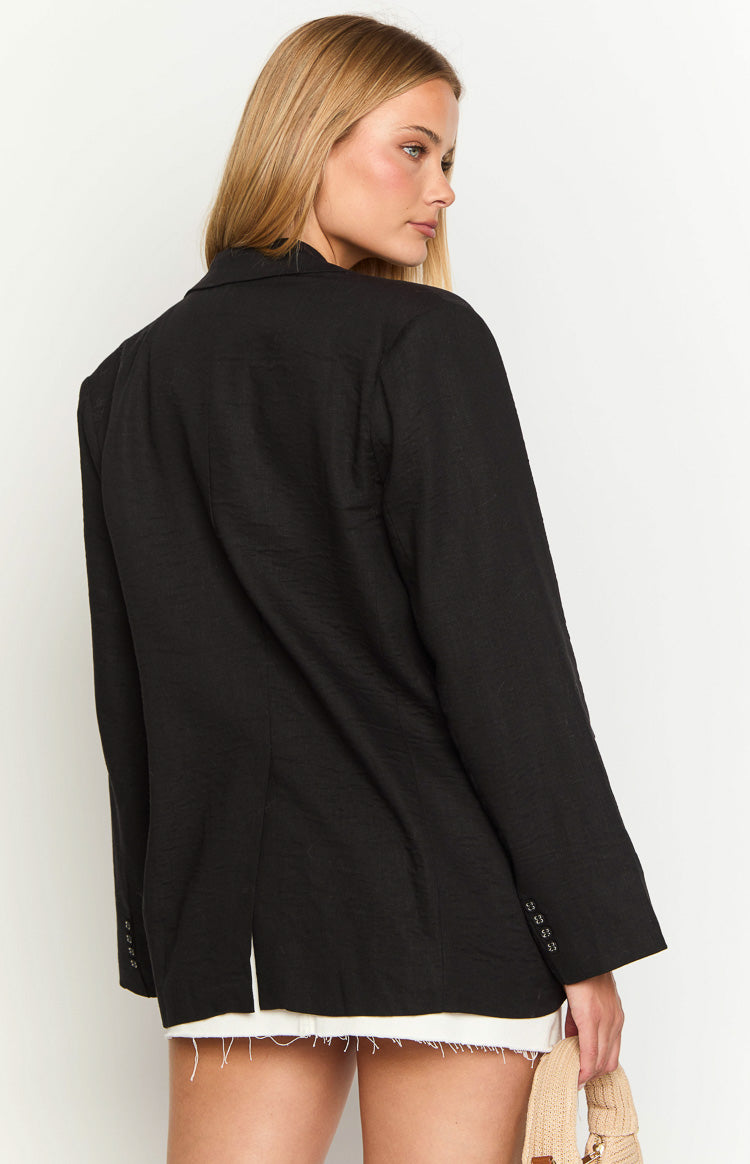 Rear view of a black linen blend blazer showing the textured fabric, single back vent, and cuff buttons