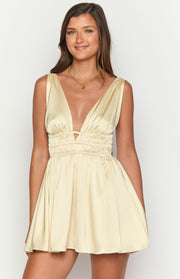 Close-up of the deep V-neck and triangular cutout on a yellow satin mini dress with shirred waist