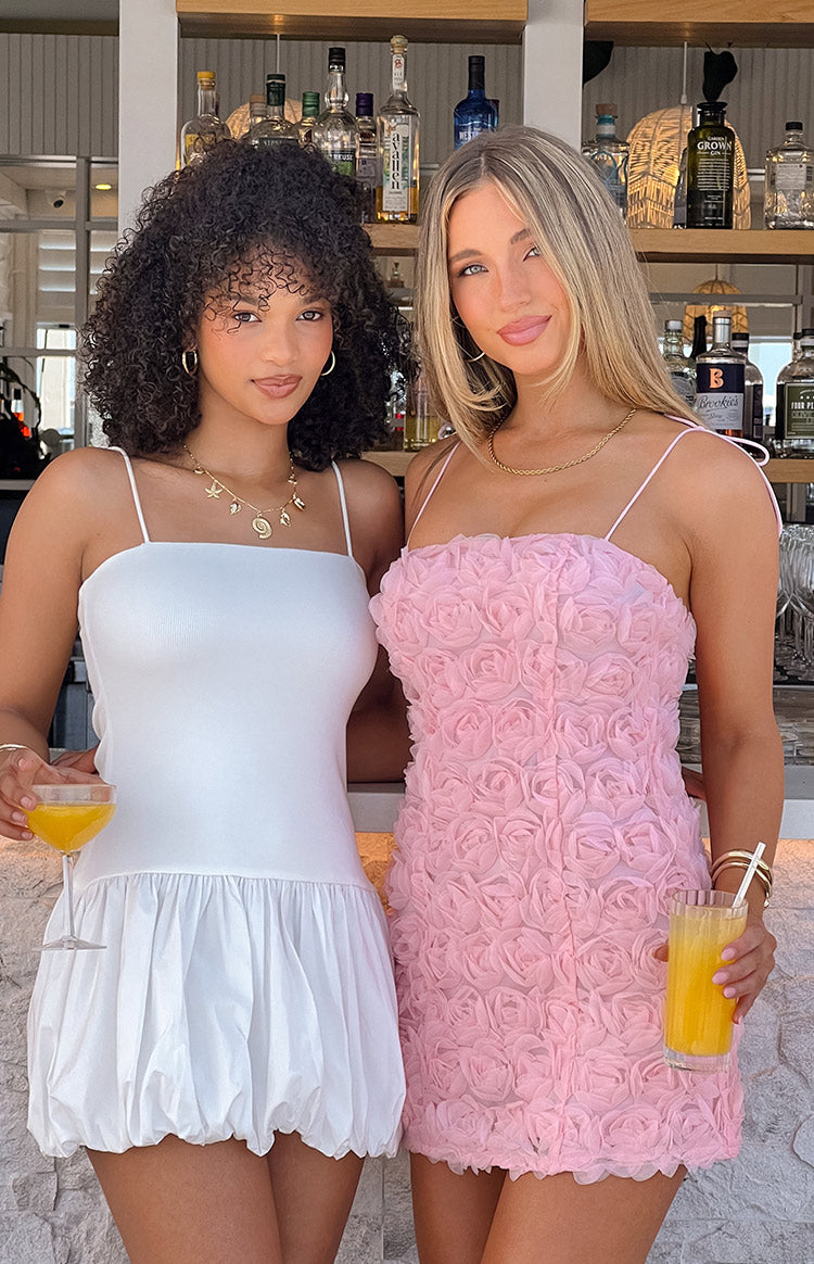 Close-up of the light pink mini dress bodice with a square neckline, thin spaghetti straps, and textured floral rosettes