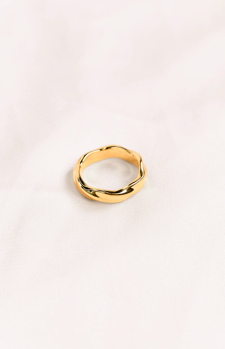 A gold-toned ring with a twisted, wavy design, giving it an organic, undulating shape.