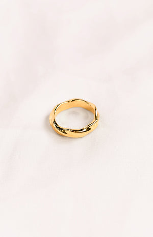 A gold-toned ring with a twisted, wavy design, giving it an organic, undulating shape.