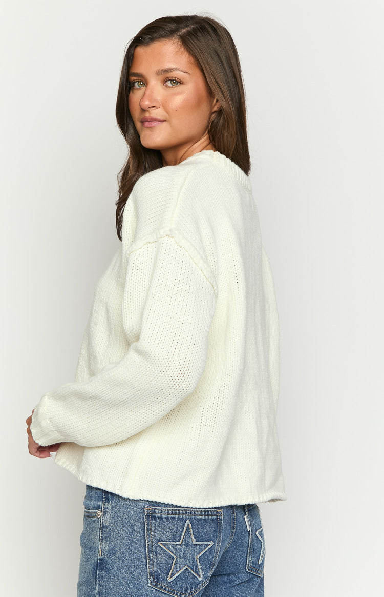 Rear view of a cream knit sweater showing the dropped shoulder seam and raw edge hem