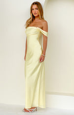 Light yellow off-shoulder maxi dress featuring a draped neckline and a long flowing skirt
