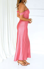 Side view of a pink off-shoulder formal dress with a draped neckline and a flowing satin skirt