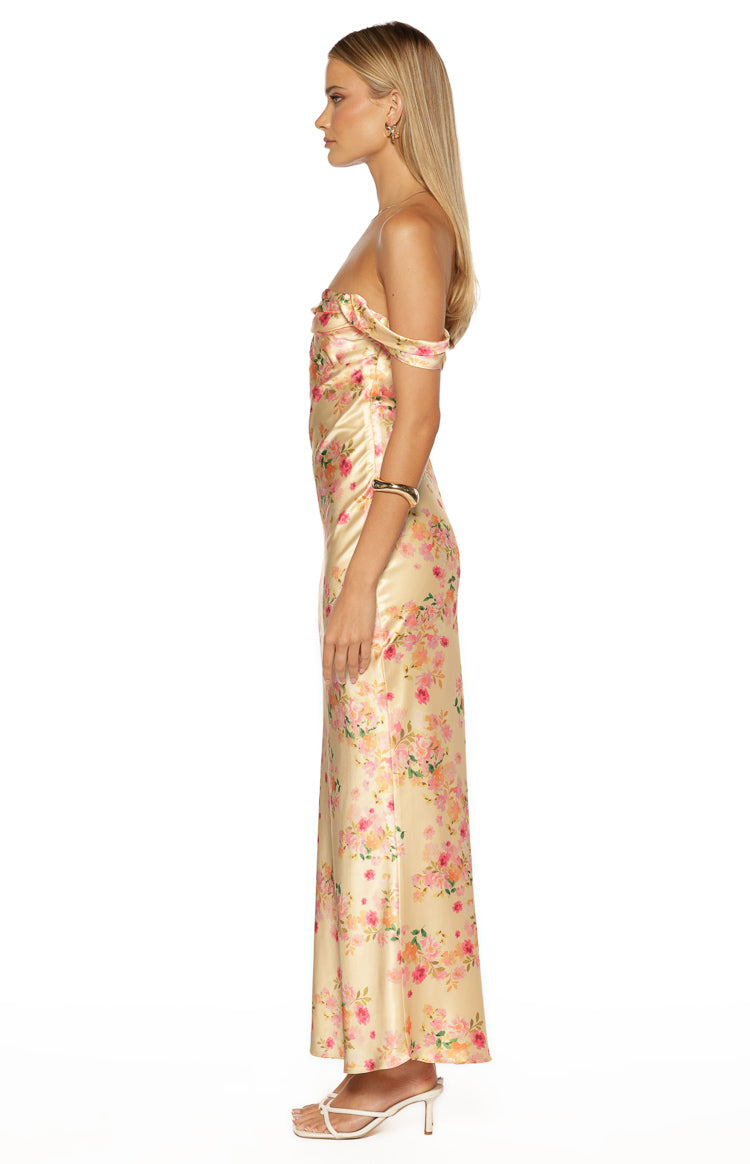 Side view of a yellow floral satin maxi dress with off-shoulder sleeves and a fitted bodice