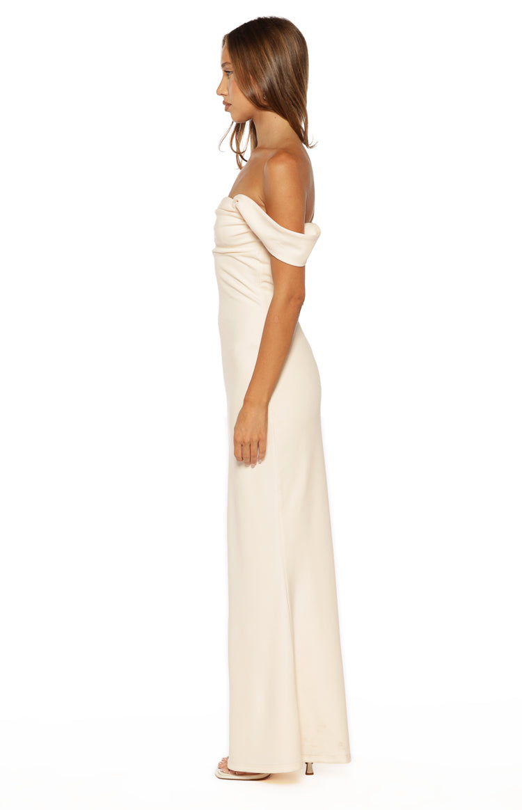 Side view of a cream crepe maxi dress with an off-shoulder neckline and draped sleeves, showing the fitted bodice and straight skirt