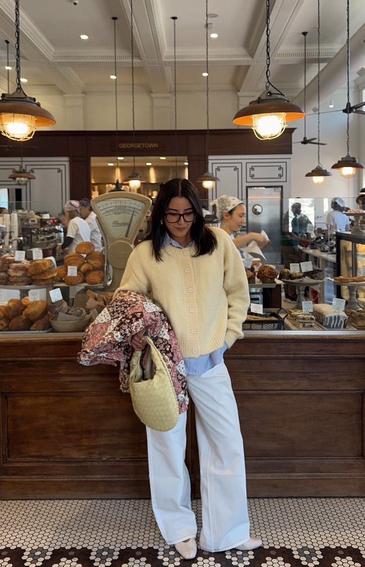 Full length view of a butter yellow button-down cardigan with a crew neck, relaxed fit, and ribbed hem