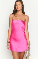 Girl showing the back of a hot pink satin mini dress. The formal dress features a stylish open cowl back that fastens with a delicate tie- making it a standout choice for homecoming.