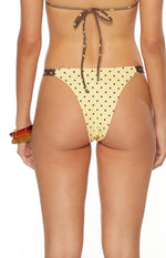 Back view of lemon yellow swim bottoms with brown spots and cheeky coverage ideal for tanning