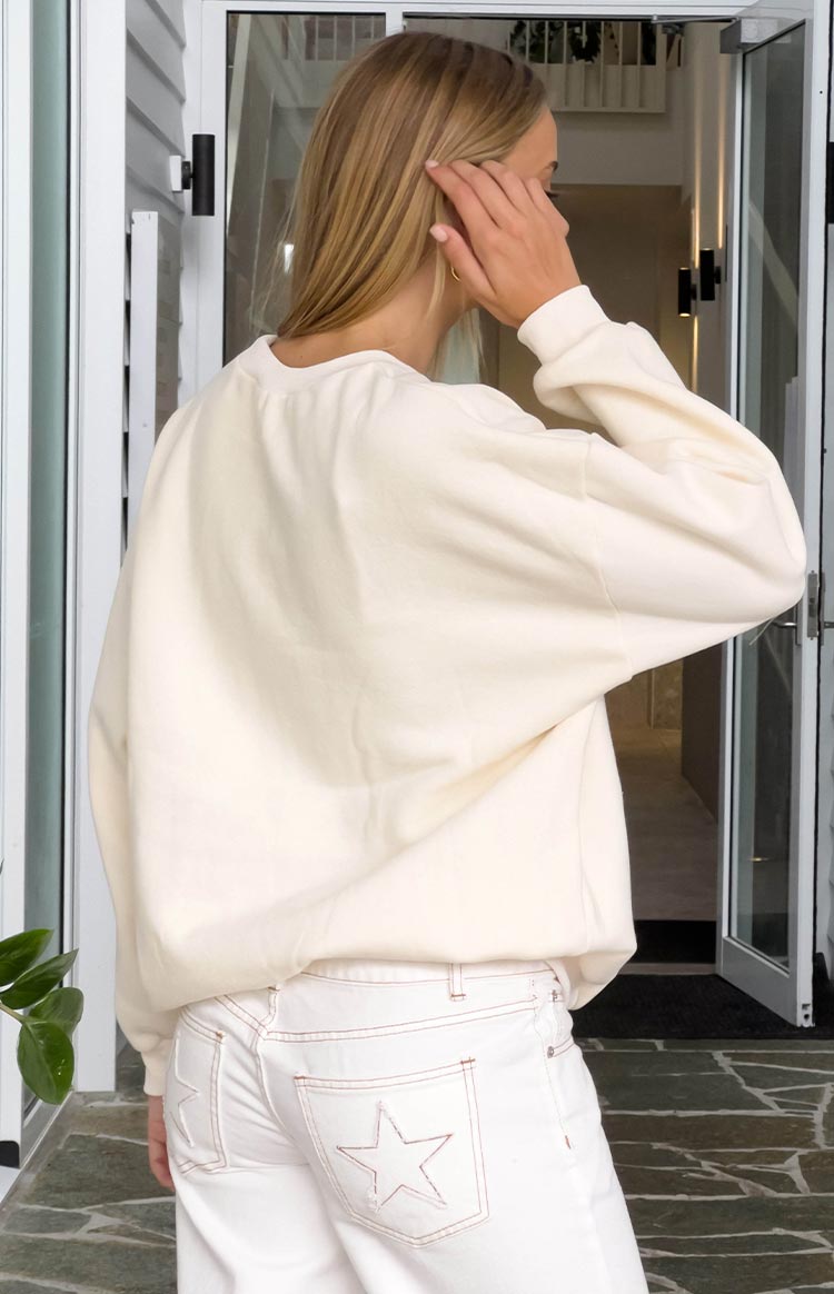 Rear view of a cream crew neck sweater with long sleeves and a relaxed fit