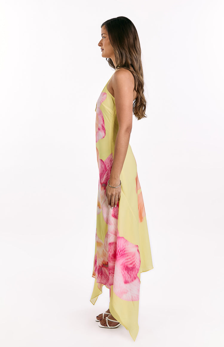Side view of a yellow hibiscus floral maxi dress with a flowy silhouette and asymmetrical hemline