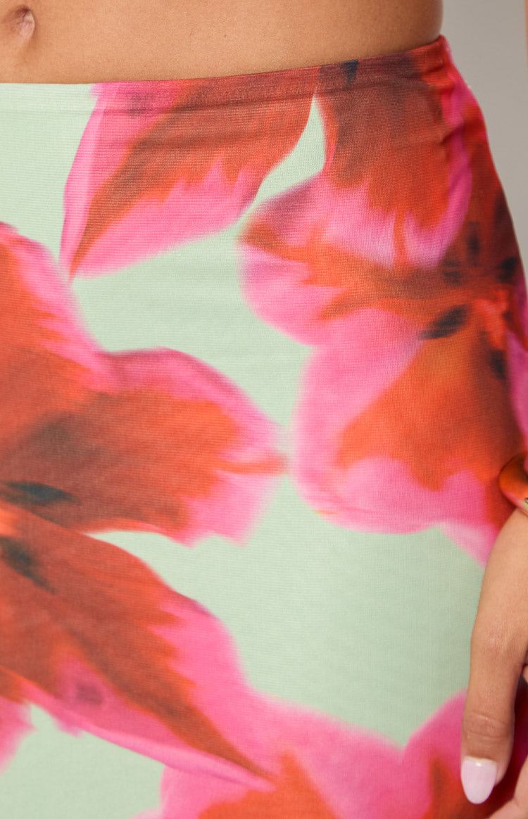 Close-up of the elastic waistband and the vibrant pink and orange floral print on a light green maxi skirt