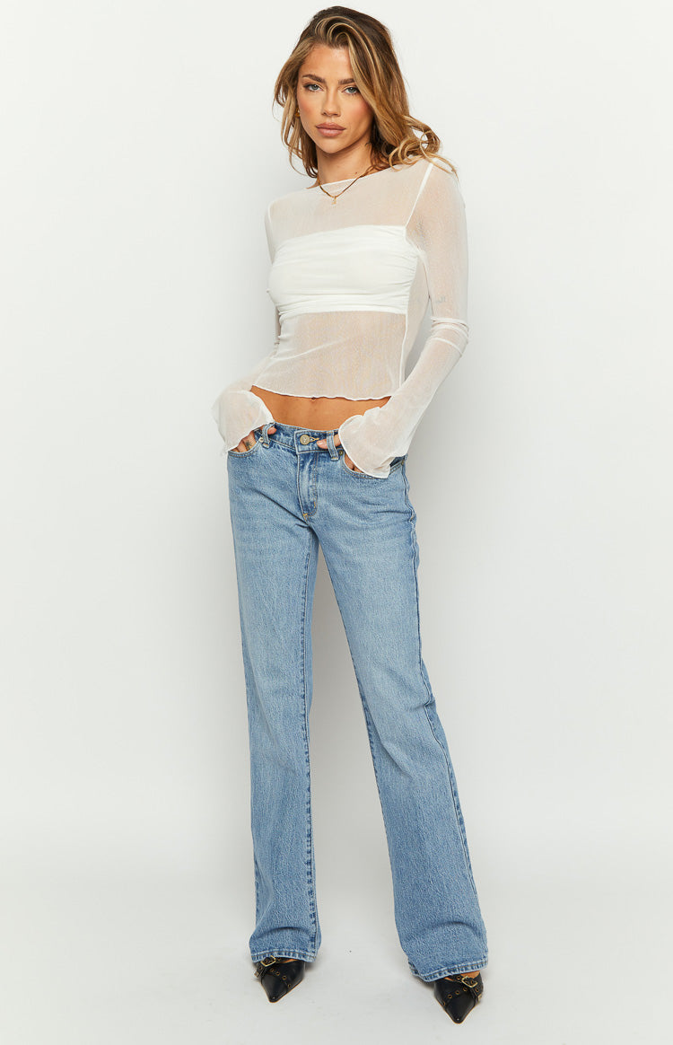 Sheer white long sleeve knit top featuring a ruched bandeau across the chest and lettuce hem