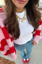 Top-down view of a pink and red checkered chunky knit cardigan with long sleeves