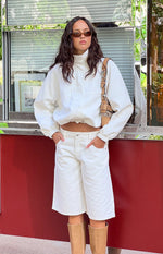 Front view of a cream funnel neck sports jacket with a full zip, cropped length, and elasticated hem and cuffs