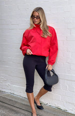 Red sports jacket with a funnel neck, long raglan sleeves, elasticated cuffs, and a relaxed fit with an elasticated hem