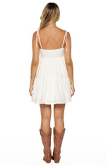 Rear view of a white mini dress with tie-up spaghetti straps and a tiered skirt