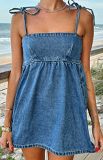 Close-up of a blue denim mini dress with a square neckline, tie straps, and gathered waist