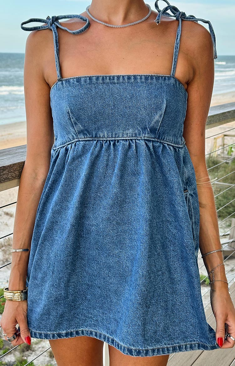 Close-up of a blue denim mini dress with a square neckline, tie straps, and gathered waist
