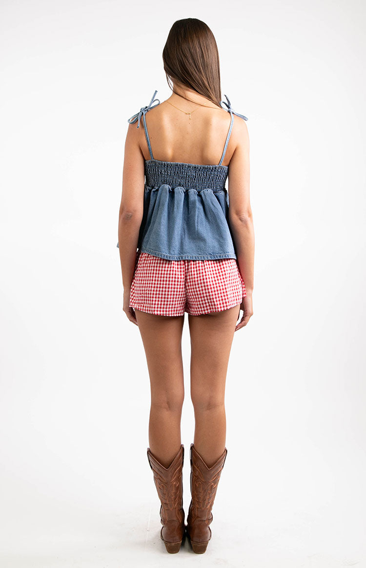 Rear view of a blue denim top with a shirred elastic back and adjustable tie spaghetti straps