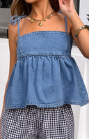 Rear view of a blue denim top with a smocked back panel and tie-up shoulder straps