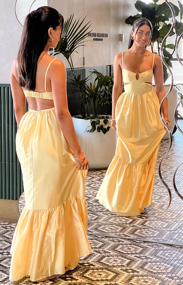 Yellow maxi dress with front keyhole and side cutouts, spaghetti straps, open back with elasticated strap, and tiered ruffle hem
