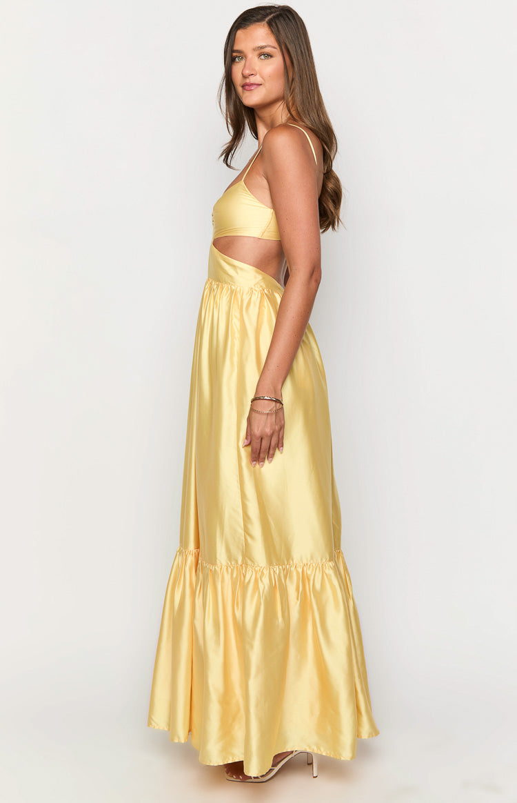 Side view of a yellow satin maxi dress with side cutouts, thin spaghetti straps, and a tiered ruffled hem