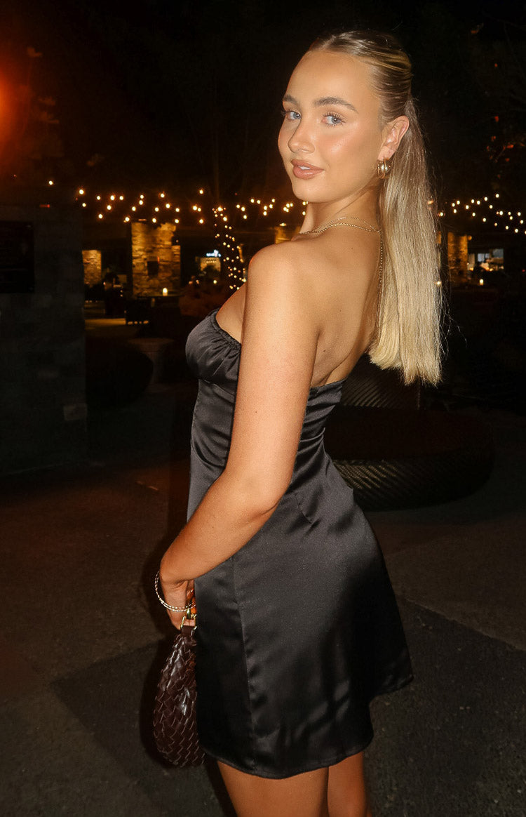 Side-back view of a black satin strapless mini dress with a ruched bust and A-line skirt