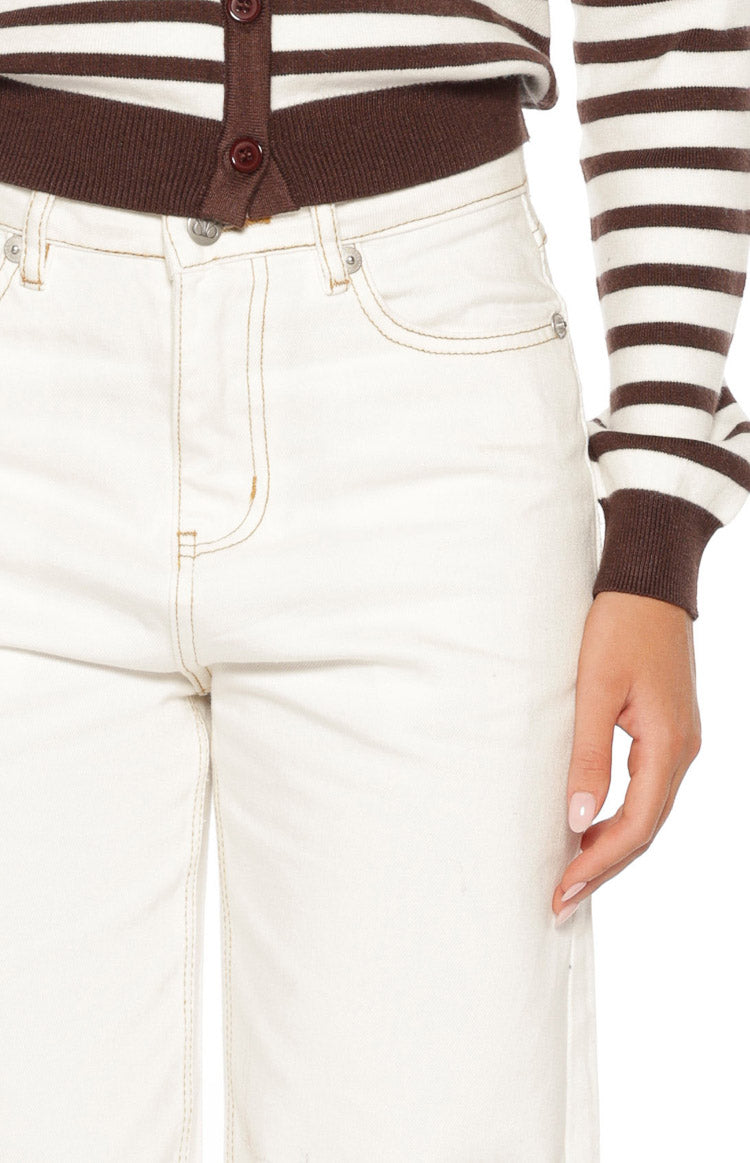 Detail shot of the white denim jeans waist with front pockets, button closure, and light brown stitching