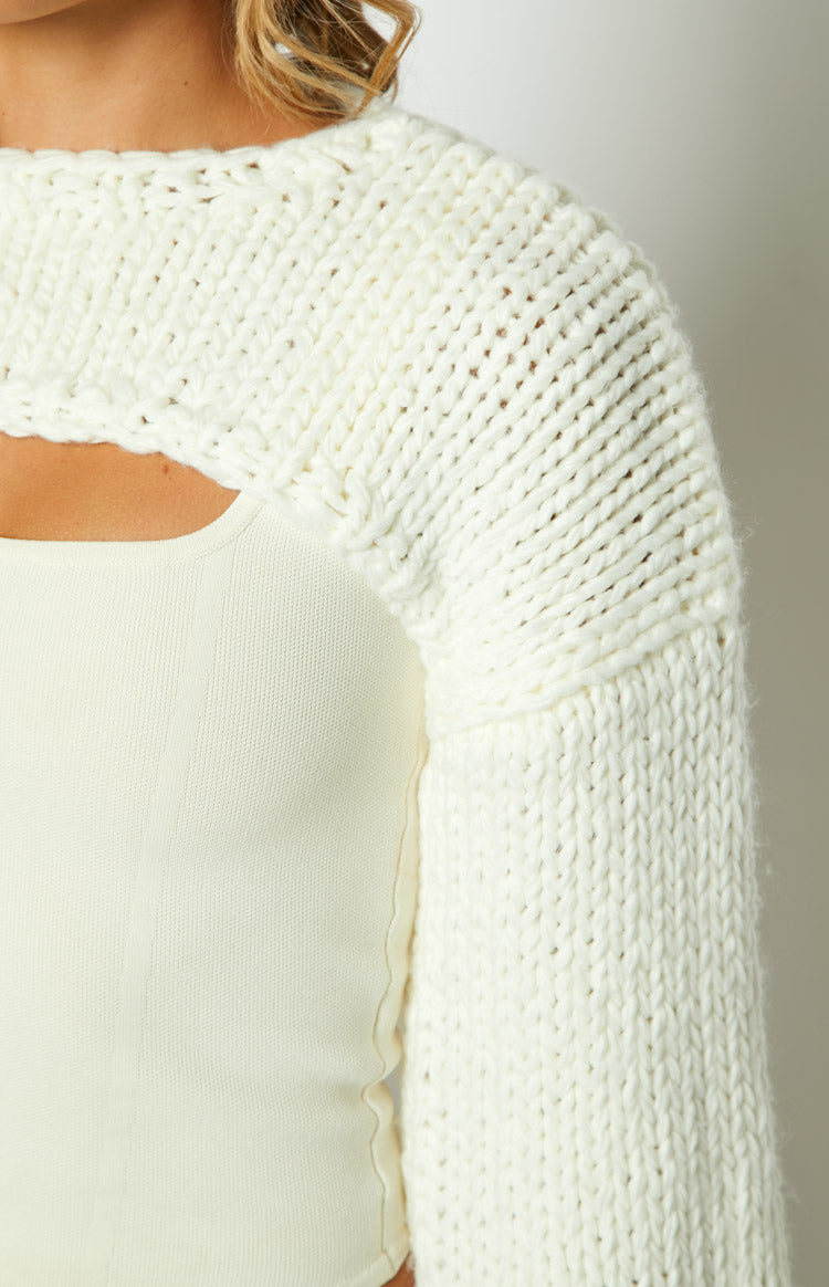 Close-up of the cream chunky knit shrug showing the thick knit texture and front cut-out