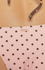 Close-up of the pink polka dot bikini bottoms with a gold 9.0 SWIM brand tag and tie string