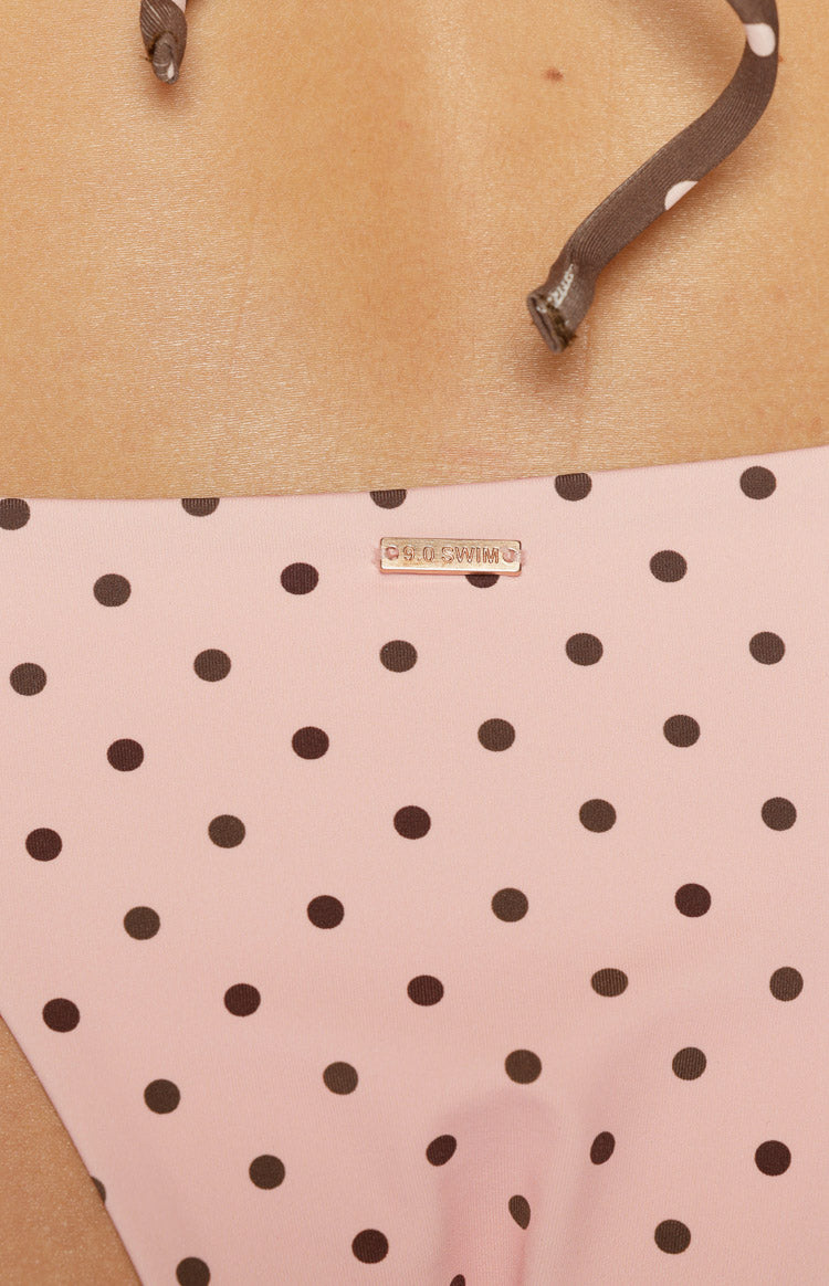 Close-up of the pink polka dot bikini bottoms with a gold 9.0 SWIM brand tag and tie string