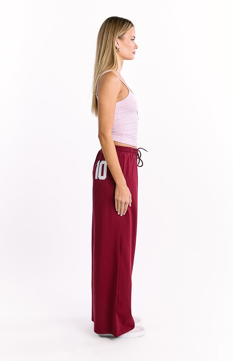 Side view of burgundy wide leg pants with a drawstring waist and white '10' graphic on the left leg