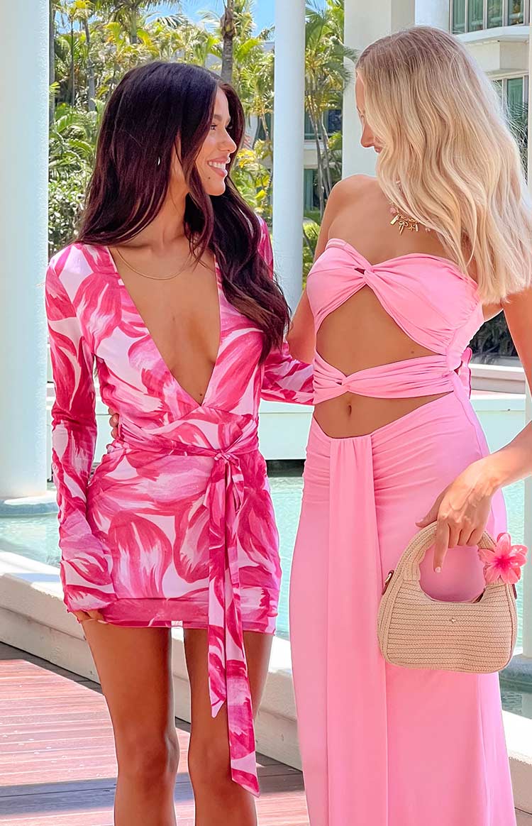 Close-up of the deep V-neckline and wrap tie waist detail on a pink floral long sleeve mini dress