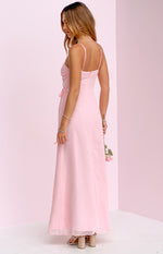 Side view of a pink sleeveless maxi dress with thin spaghetti straps, a ruched side bodice, and a flowy sheer overlay skirt