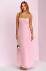 Front view of a pink sleeveless maxi dress with a ruched square neckline, thin straps, a side tie, and a flowy sheer overlay skirt