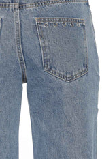 Back pocket detail of mid-wash jeans with a row of silver eyelets